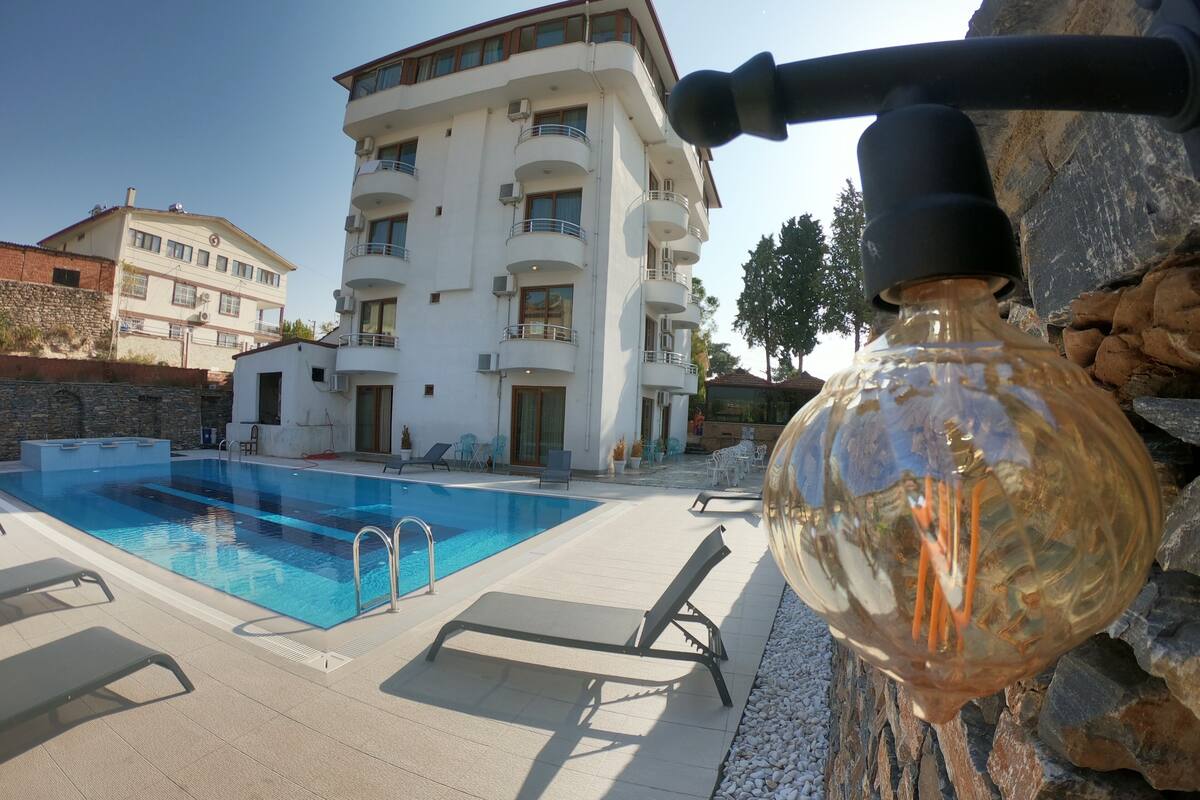 A swimming pool with lounge chairs and a building in the background.