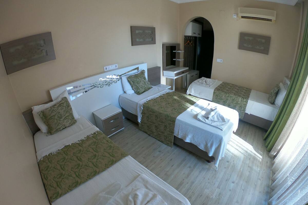 A hotel room with two single beds, a small desk, and a mirror.