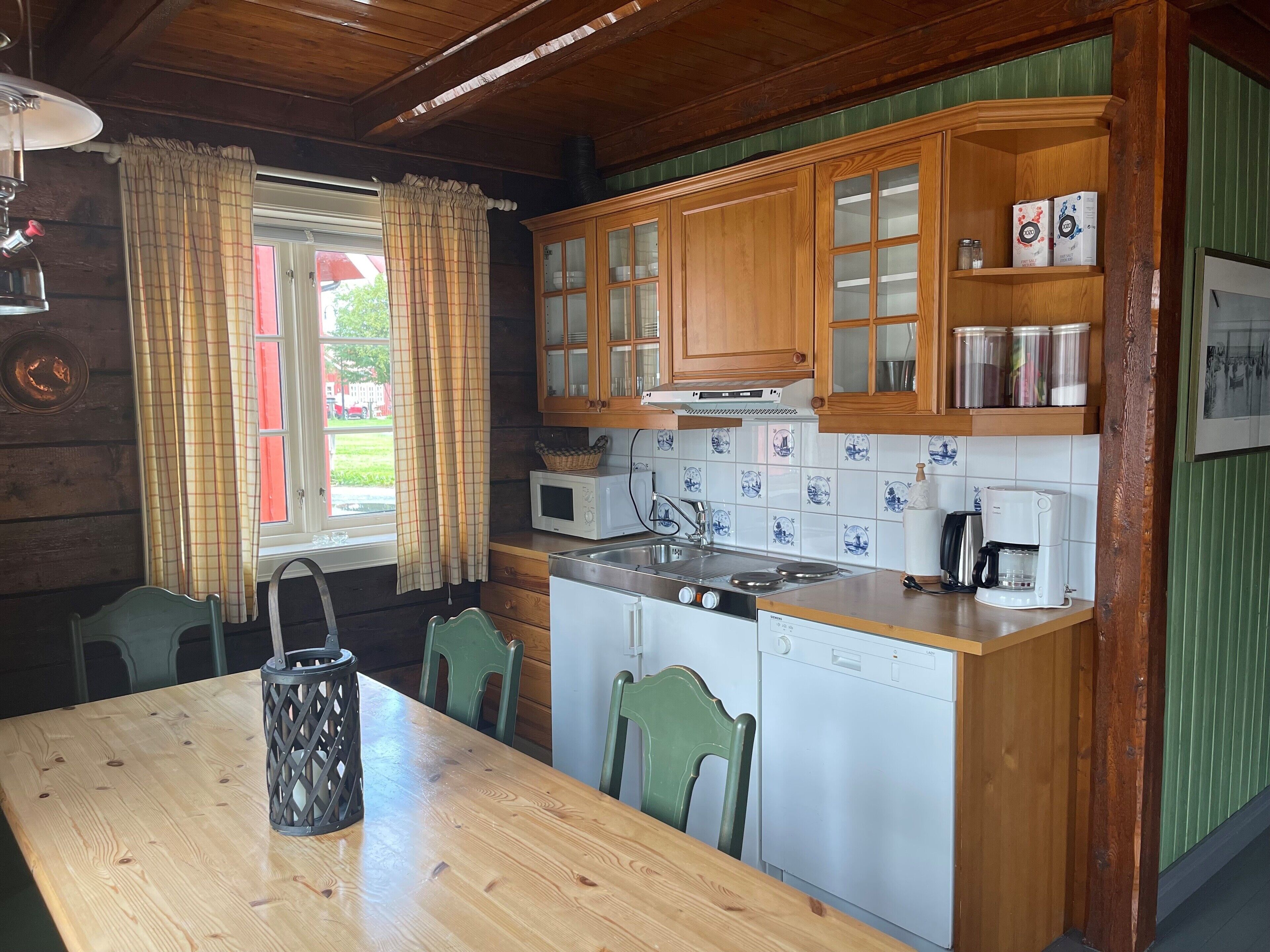 Une cuisine de style rustique, avec des éléments en bois, comprenant une table en bois, des chaises, un four à micro-ondes, une cuisinière et une machine à café.