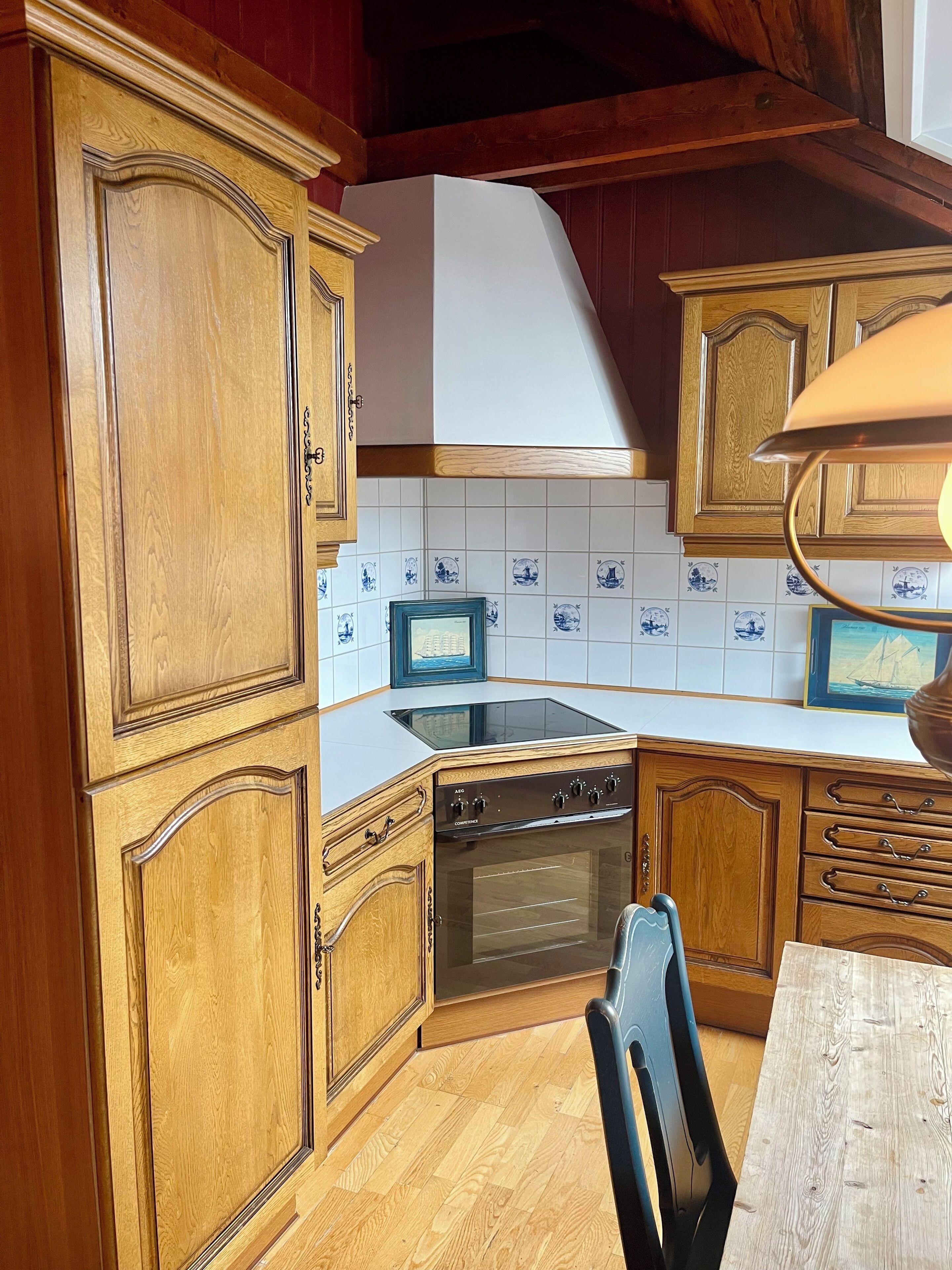 Een keuken met houten kastjes, een ingebouwde oven, een magnetron en een betegelde spatwand.