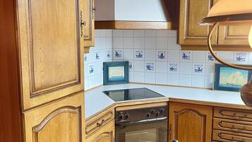 Een keuken met houten kastjes, een ingebouwde oven, een magnetron en een betegelde spatwand.