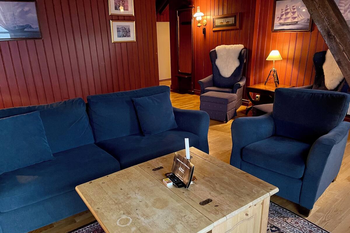 A cozy room with a blue sofa, a matching armchair, and a wooden coffee table with a remote control.
