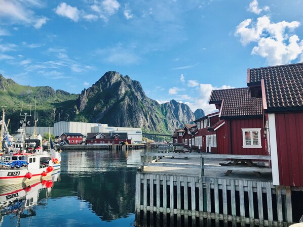 Un puerto con barcos, un muelle de madera y edificios rojos con ventanas blancas.