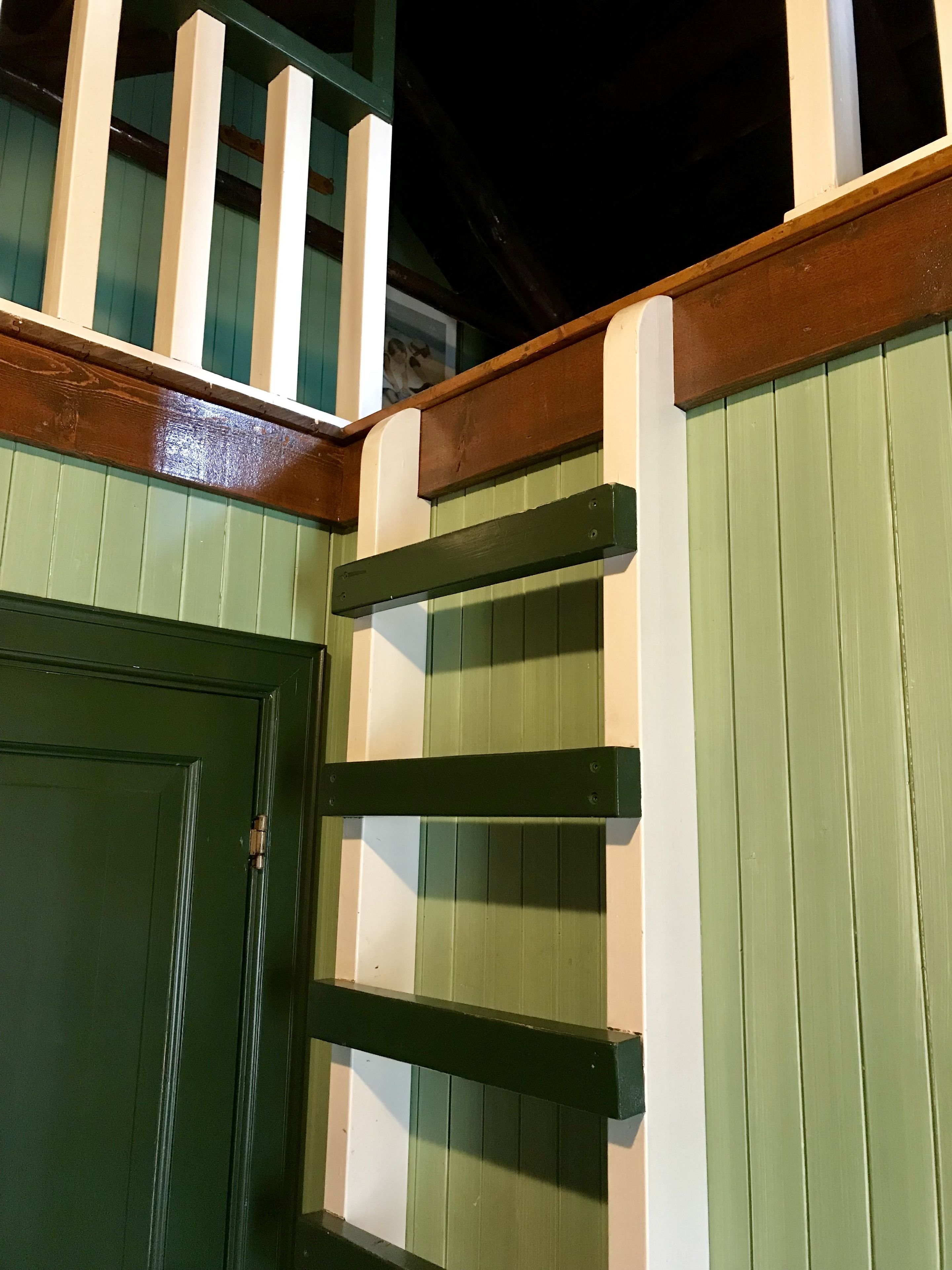 A green door with a white frame and a wooden handrail.