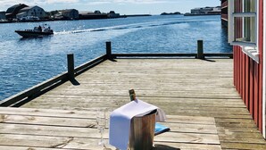Une terrasse en bois avec une table, une bouteille de champagne et un verre.
