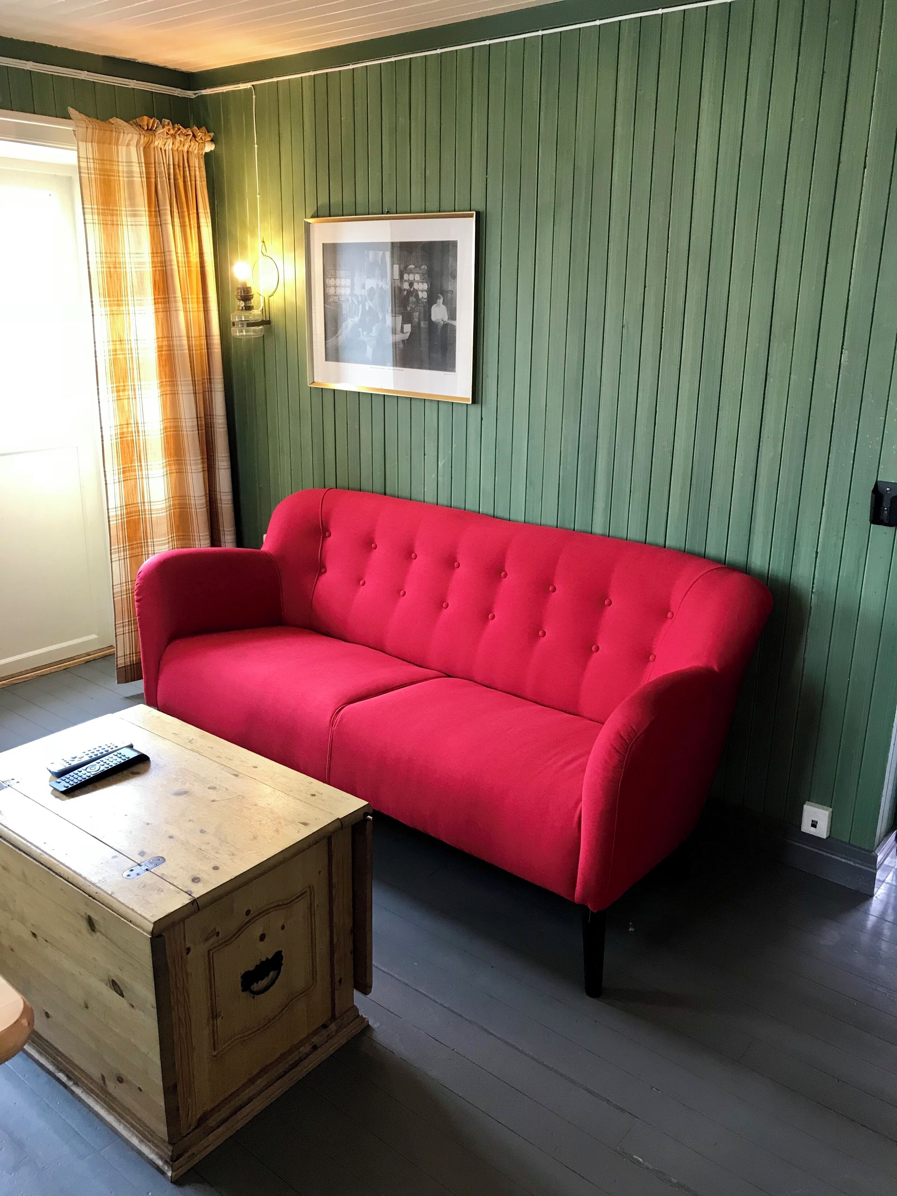 Una habitación con un sofá rojo, una mesa de centro de madera y un cuadro enmarcado en la pared.