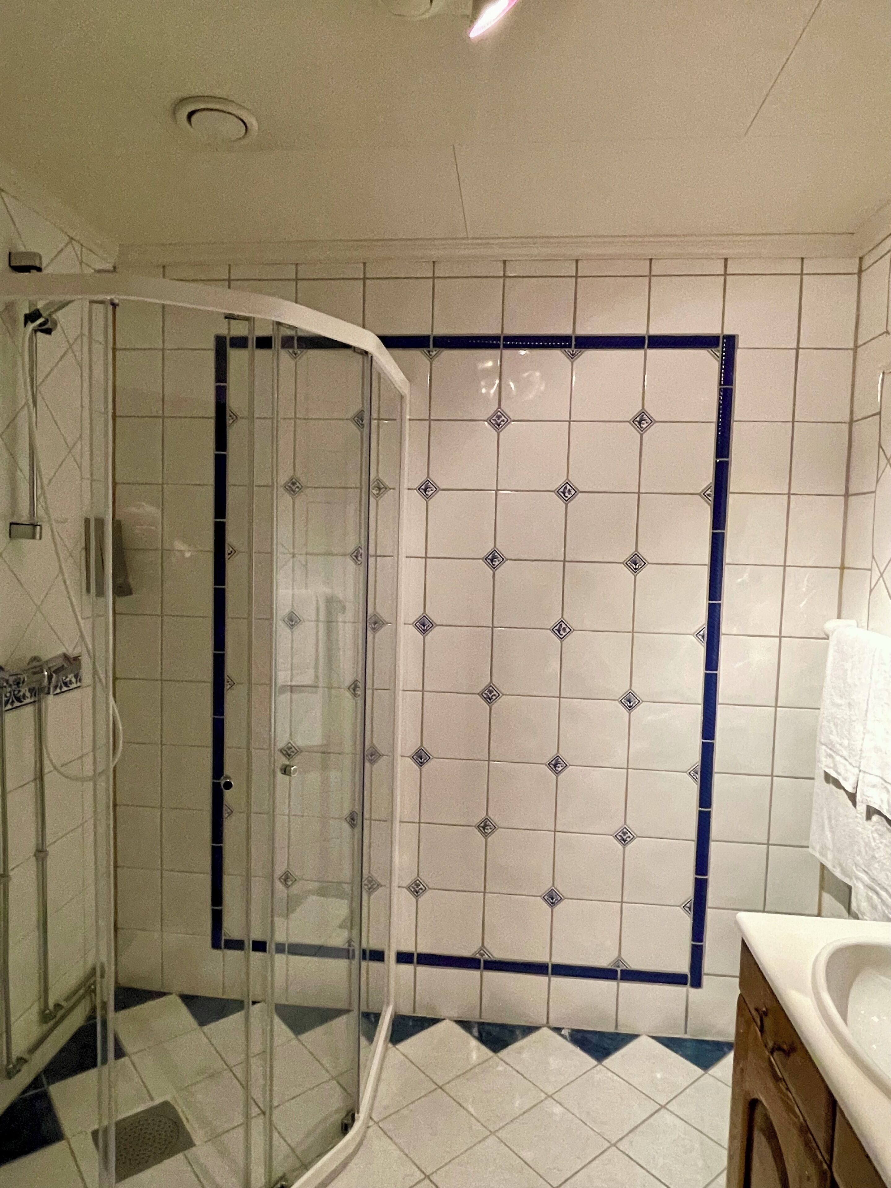 A bathroom with a shower enclosure, tiled walls, and a sink.