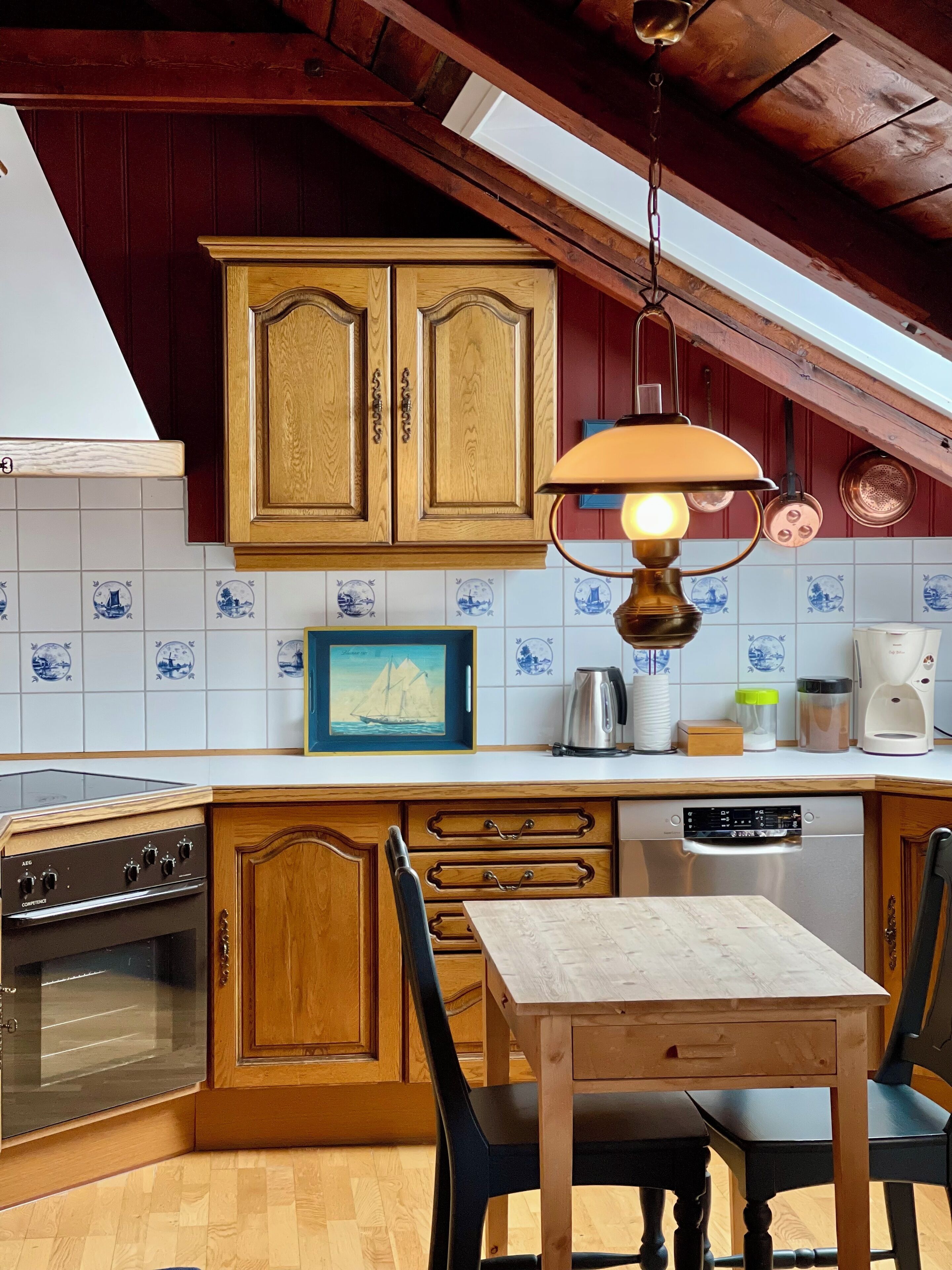 Una cocina con armarios de madera, estufa, lavavajillas y una mesa de comedor con sillas.