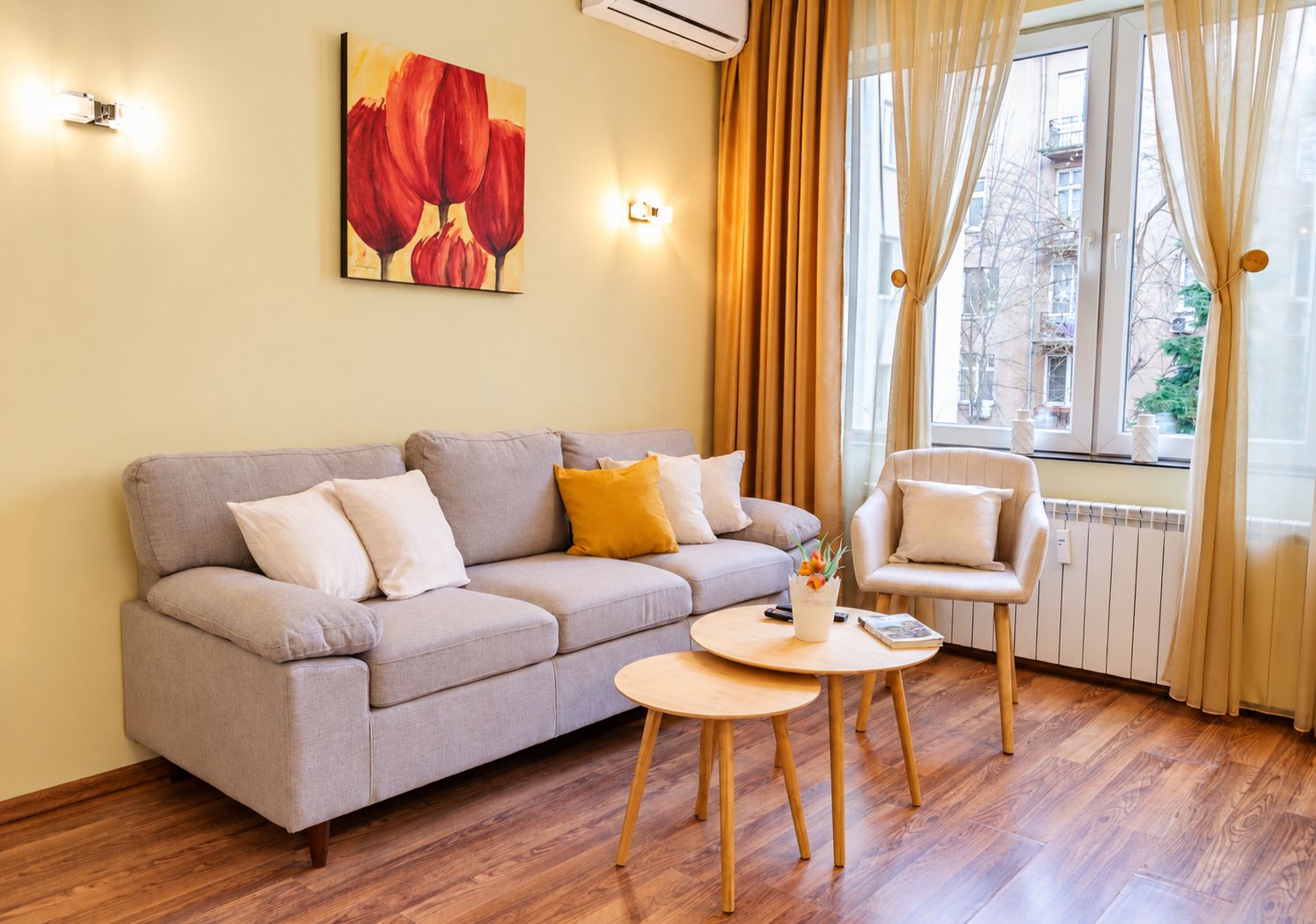 Una sala de estar con un sofá, una silla, una mesita y una ventana con cortinas.