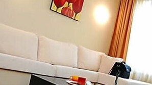 A modern living room with a white sofa, a black coffee table, and a painting of red flowers on the wall. - BIZ Apart Sofia (Sofia)