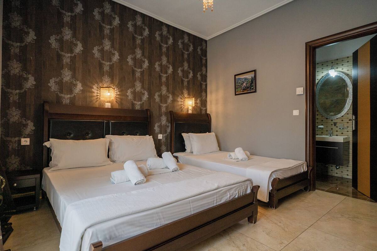 A hotel room with two beds, a large mirror, and a view of the bathroom.