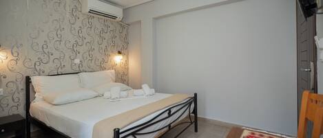 Un dormitorio con cama, mesita de noche, aire acondicionado instalado en la pared y un diseño decorativo en la pared.