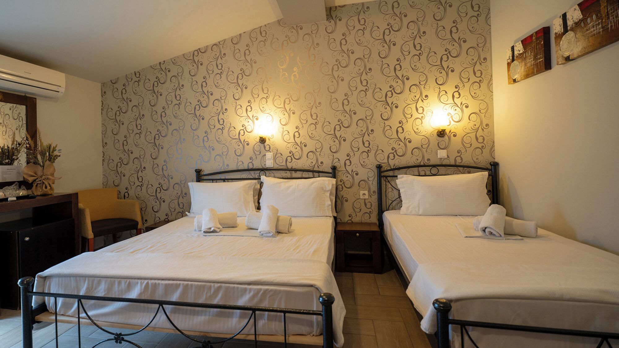 A hotel room with two beds, a desk, and a chair.