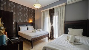 A hotel room with two beds, a wooden headboard, a nightstand, a lamp, and a wall-mounted air conditioner. - Toti Boutique Rooms  (Kalabaka)