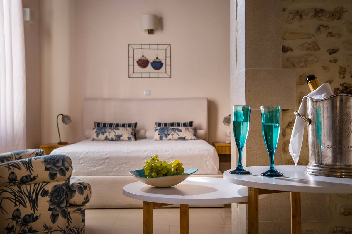 Une chambre d’hôtel avec un lit, un panier de fruits, deux verres et un mini-bar.