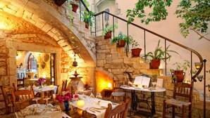 Un restaurante acogedor con paredes de piedra, muebles de madera y plantas en macetas.