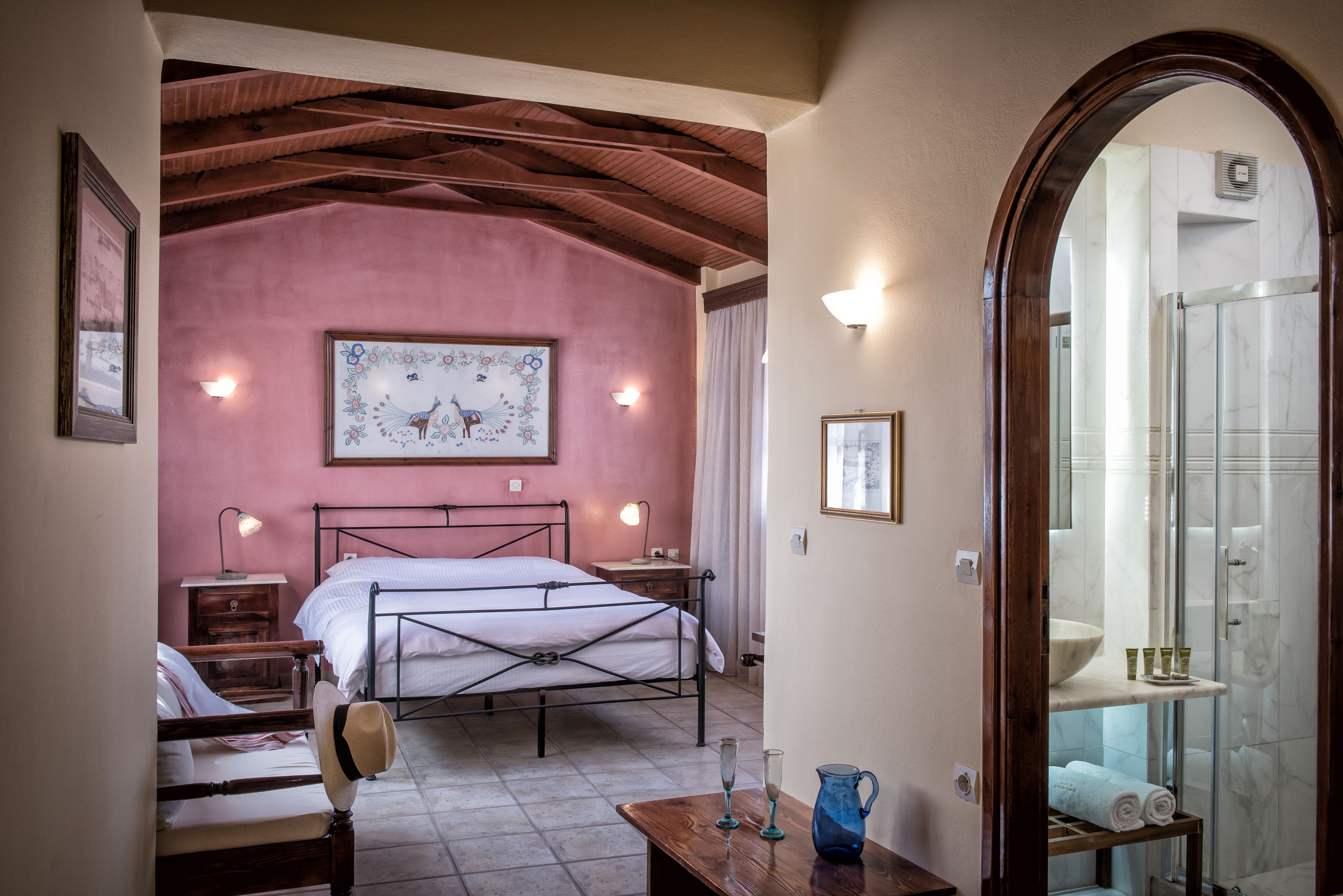 A bedroom with a bed, bedside tables, a mirror, and a bathroom visible through an archway.