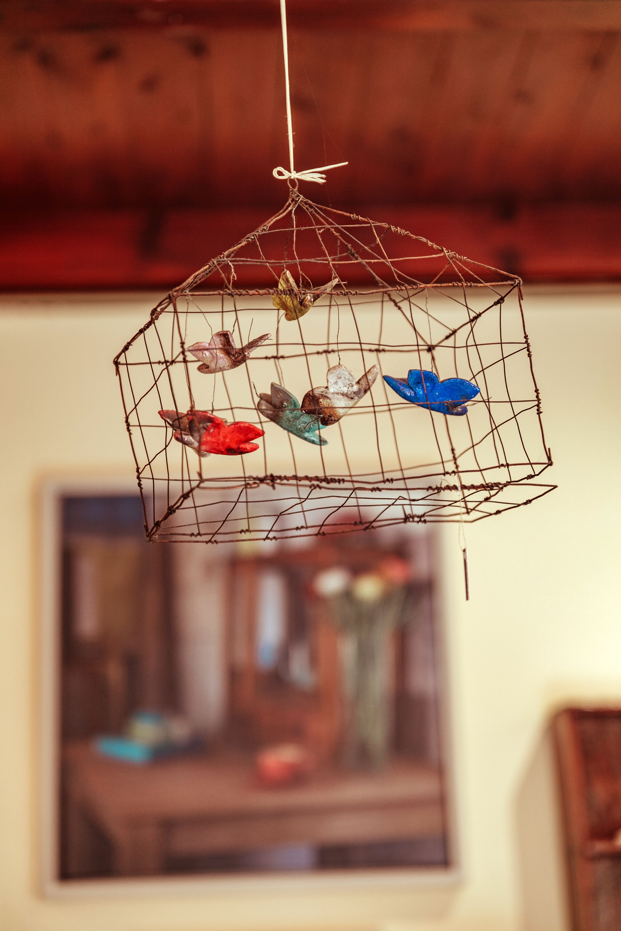 A hanging birdcage with colorful glass birds.