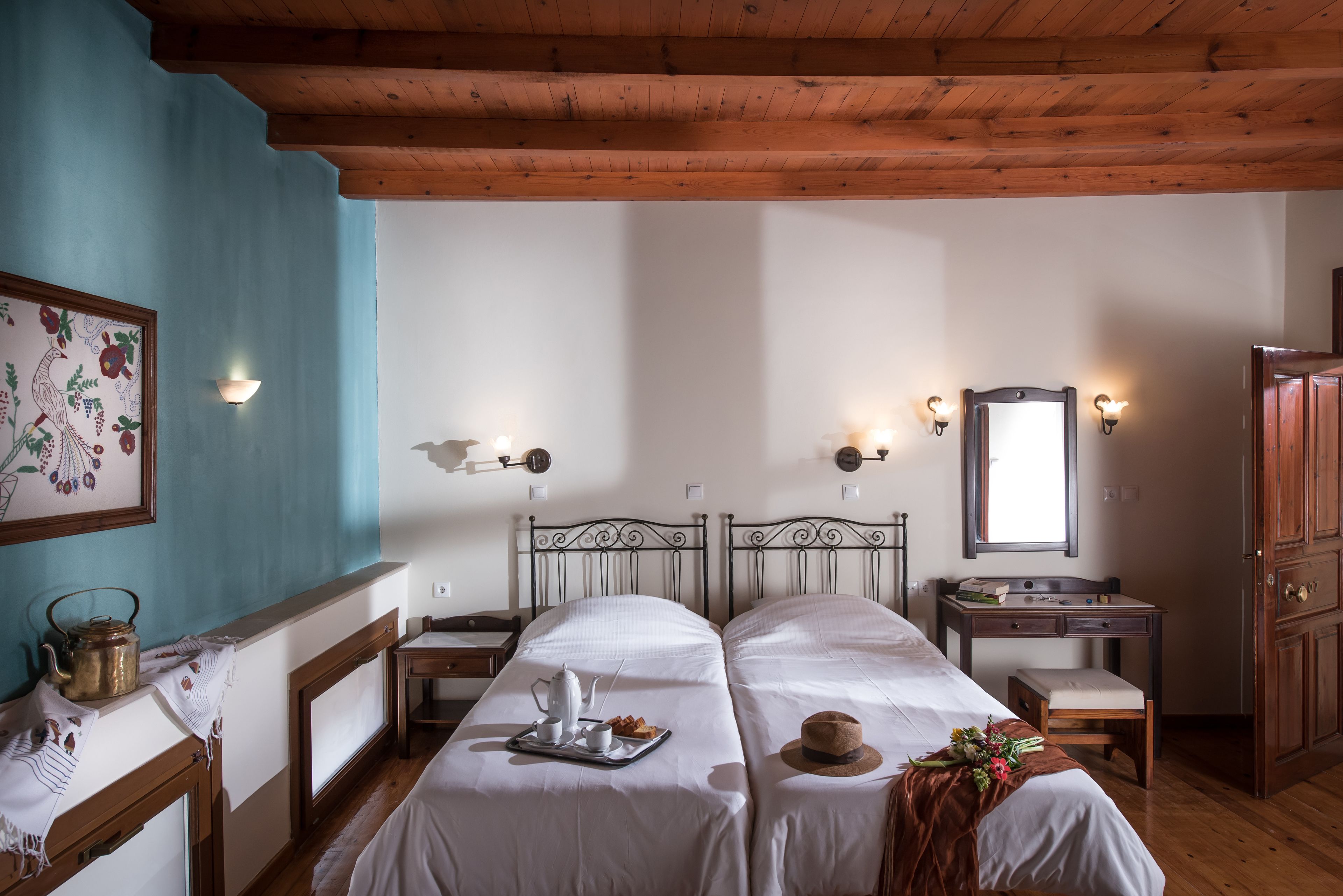 Une chambre avec deux lits, un bureau en bois, un miroir et une horloge murale.