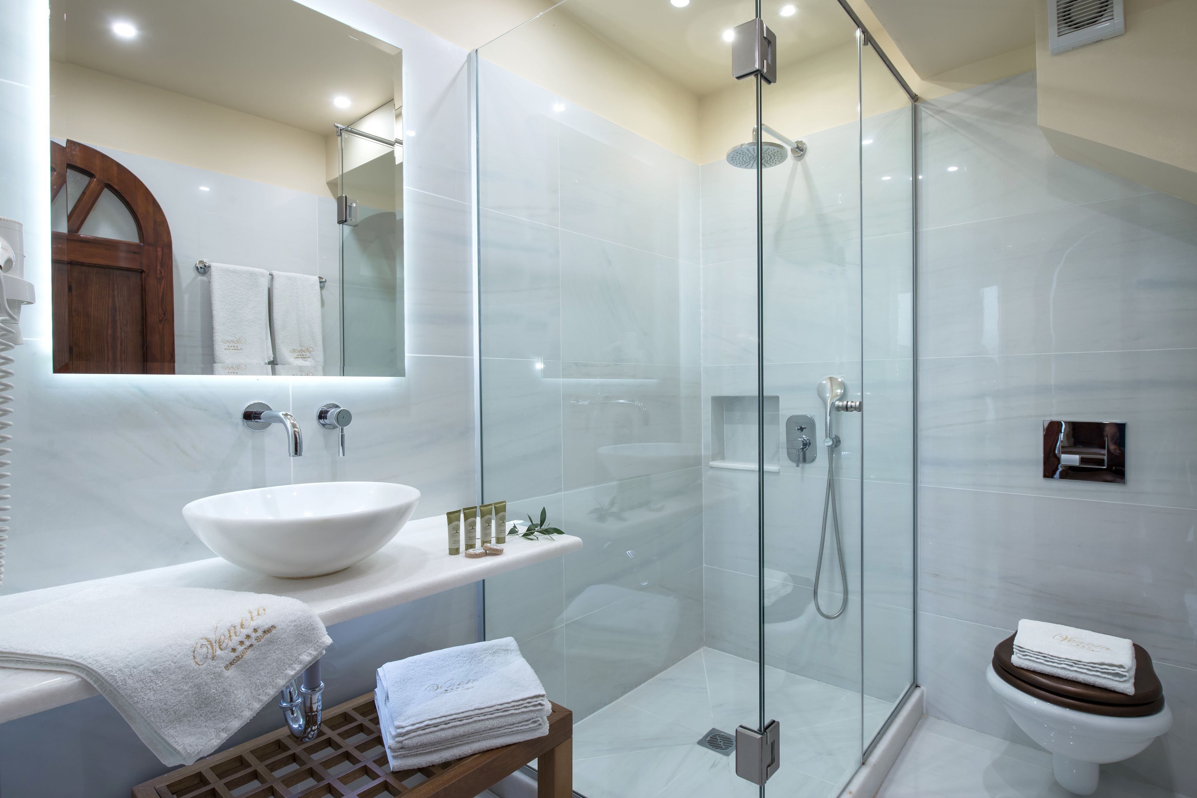 A modern bathroom with a glass-enclosed shower, a white sink, and a wooden vanity.