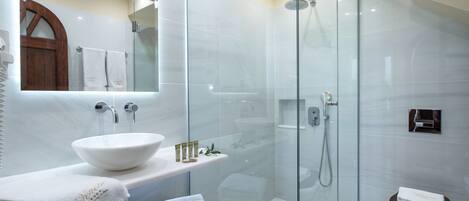 A modern bathroom with a glass-enclosed shower, a white sink, and a wooden vanity.
