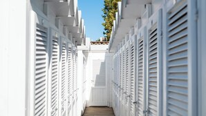 A narrow corridor with white shutters, leading to a door at the end. - Ausonia (Follonica)