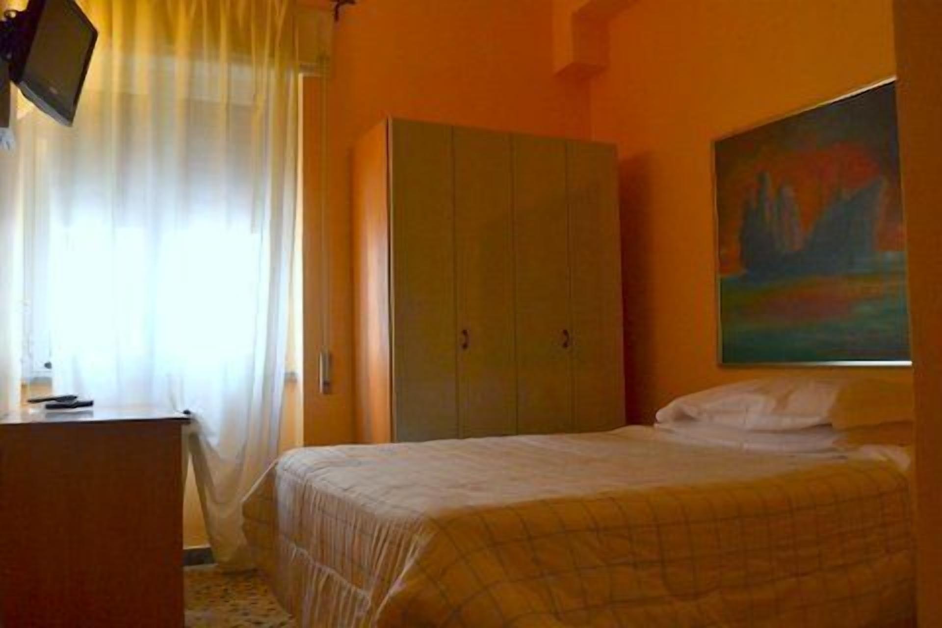 A bedroom with a bed, a wardrobe, a desk, and a painting on the wall.