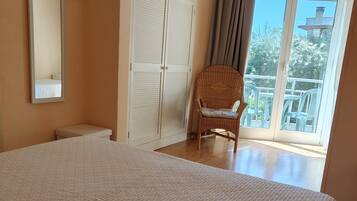 Ein Schlafzimmer mit einem großen Bett, einem Sessel, einem Kleiderschrank und einem Balkon mit Aussicht.