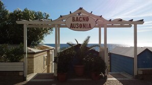 A pergola with a sign reading "BAGNO AUSONIA" in front of a building with a view of the sea. - Ausonia (Follonica)