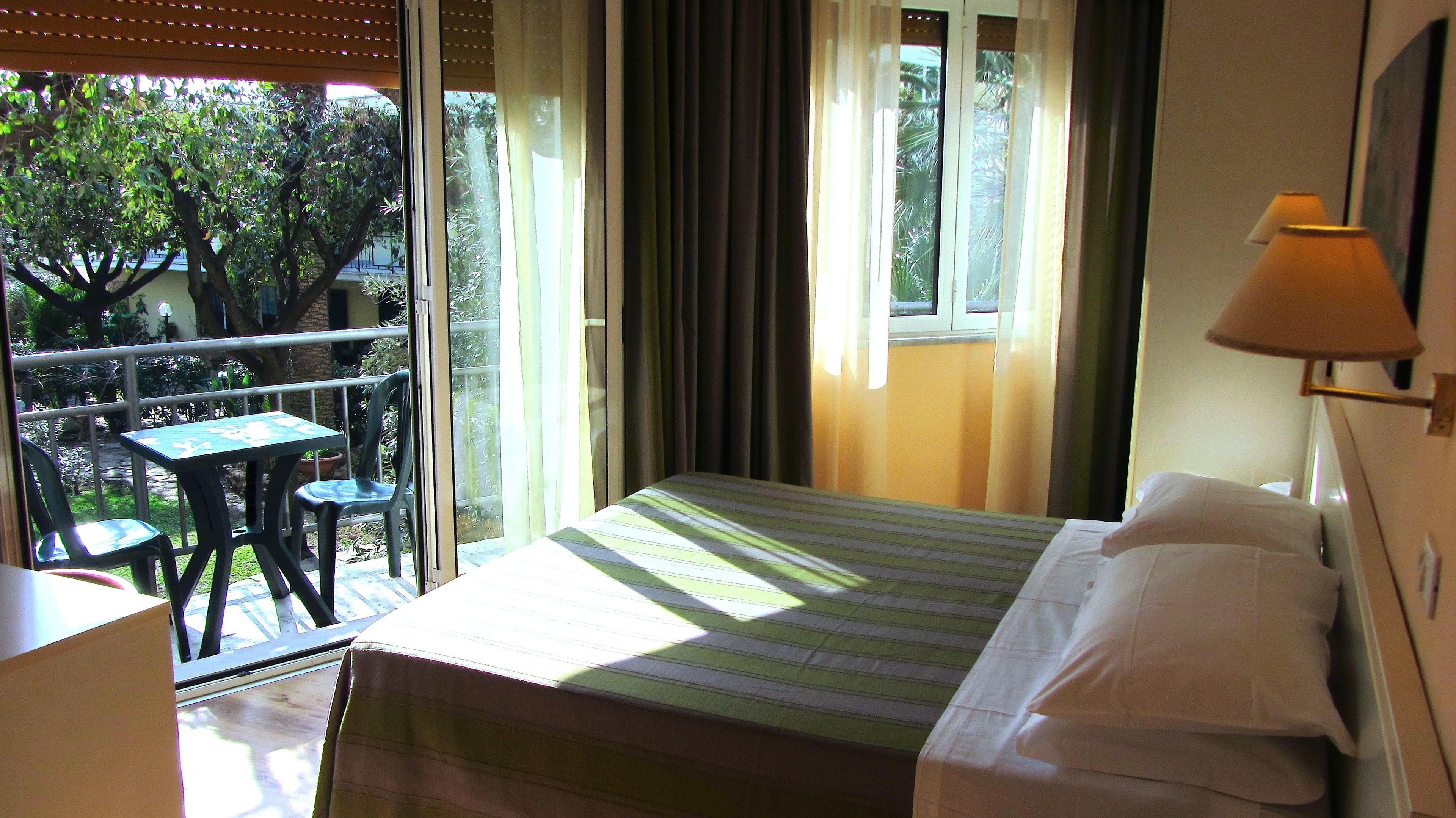 Una camera d'albergo con un letto, un tavolo, sedie e vista sul verde.