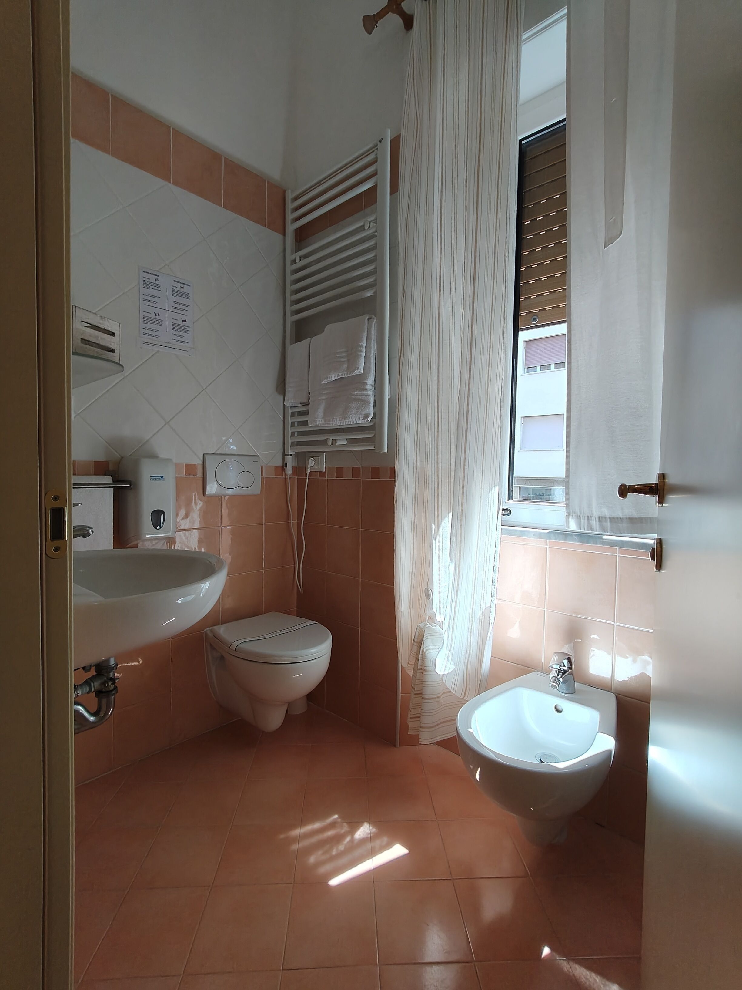 Casa de banho com lavatório, sanita, bidé e porta-toalhas.