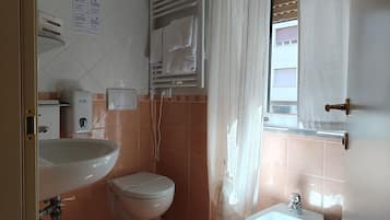Casa de banho com lavatório, sanita, bidé e porta-toalhas.