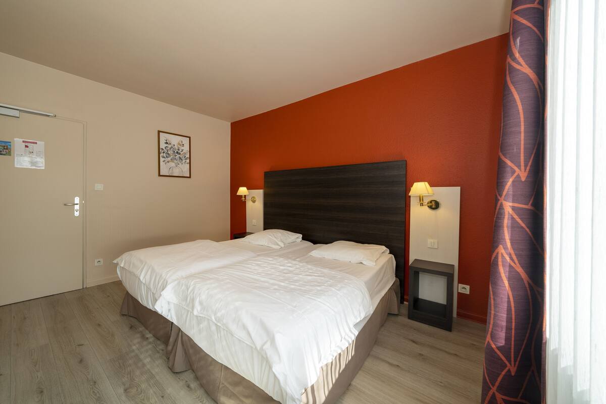 Une chambre à coucher avec un lit, une table de chevet, une lampe et une porte.