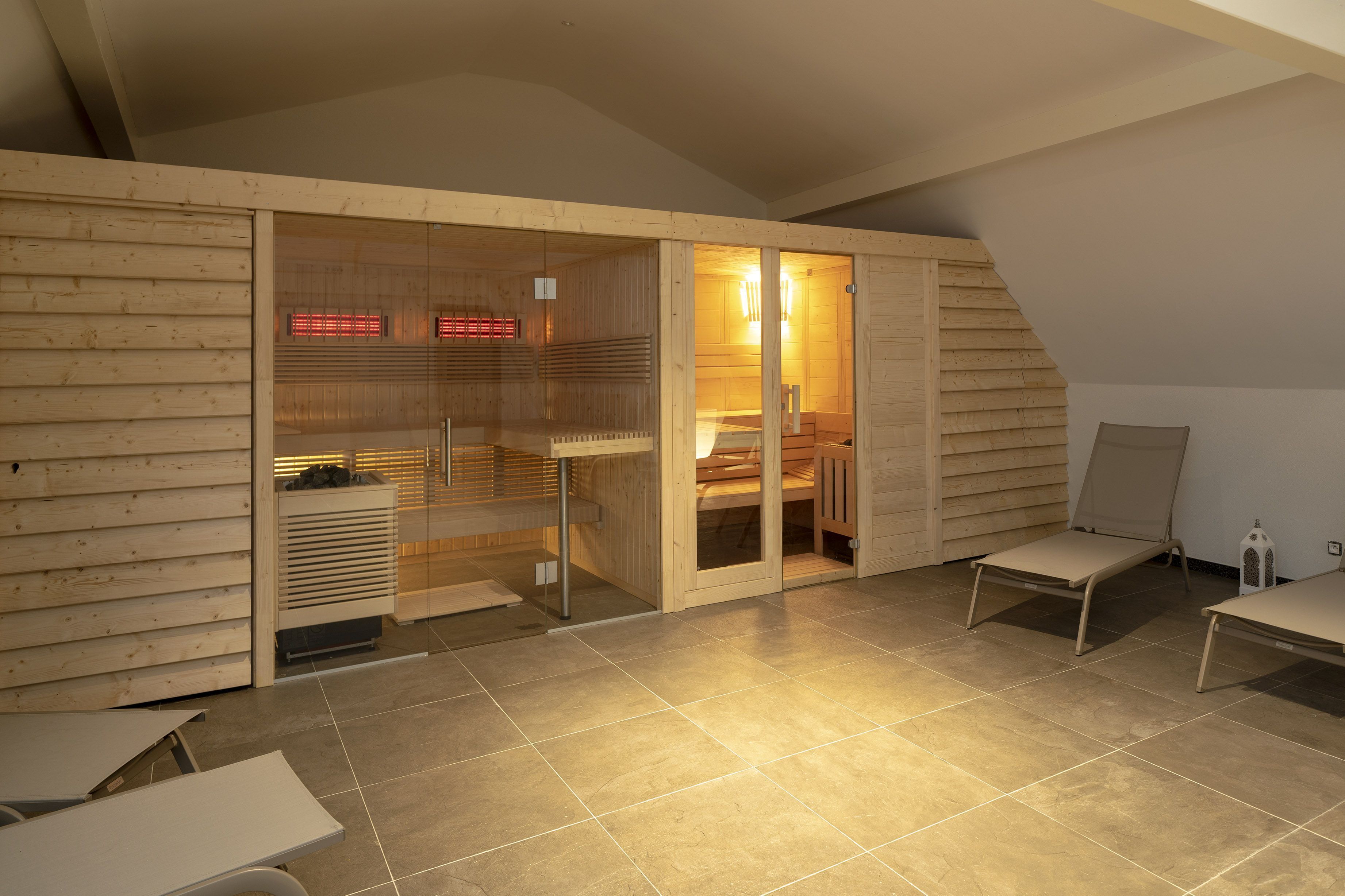A modern, well-lit room with a wooden slatted wall, a glass door leading to a bathroom, and two chairs.