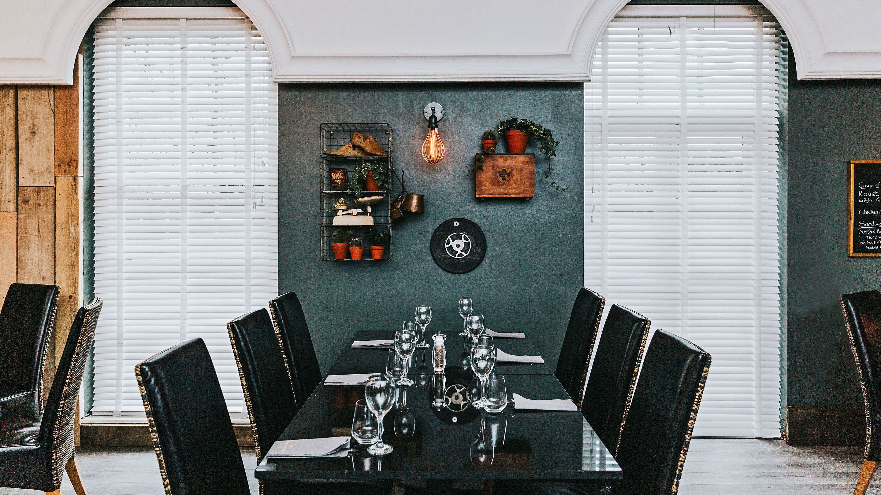 A dining area with a table set for six, surrounded by black chairs.