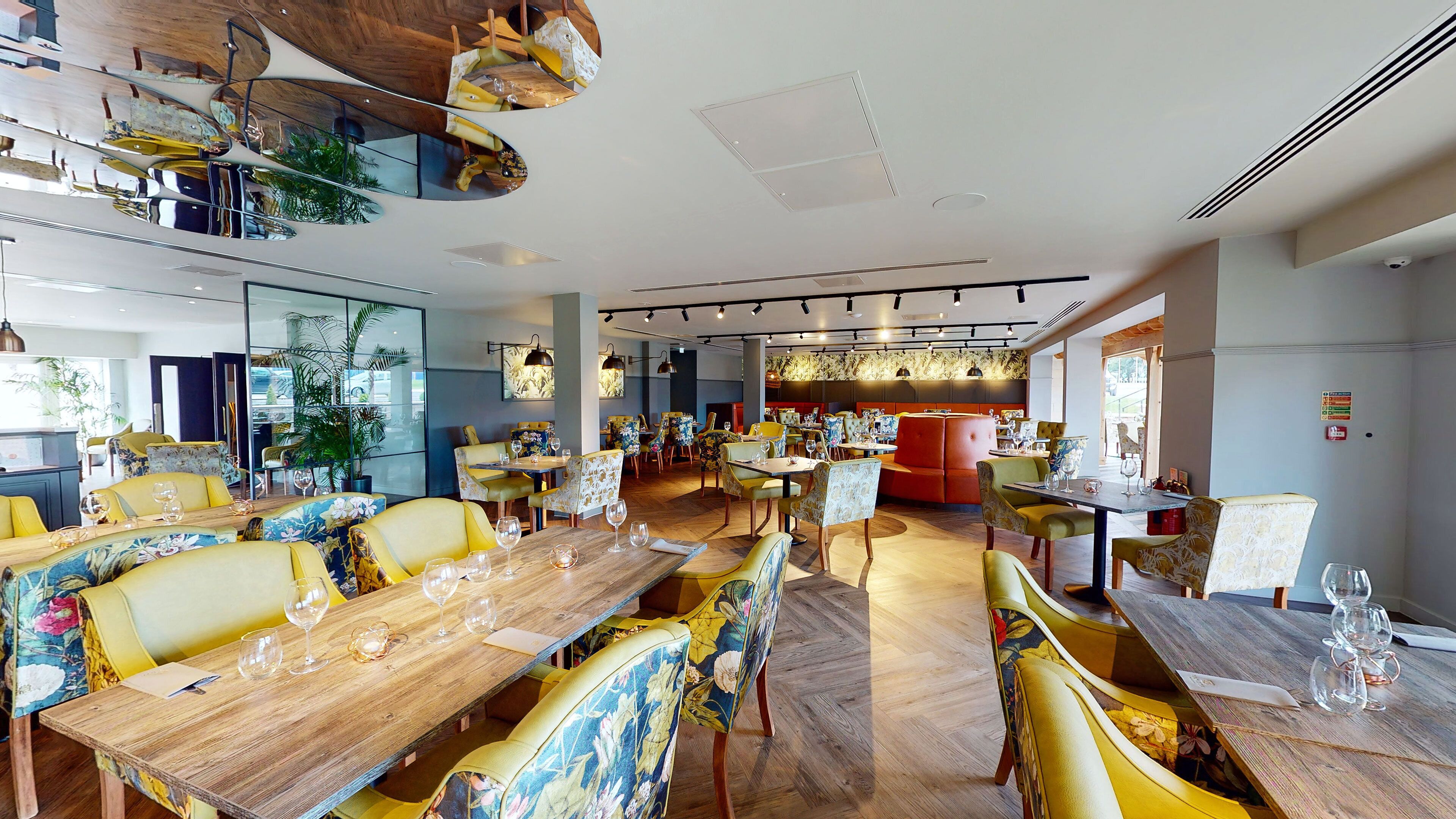A restaurant with multiple dining areas, wooden tables, and chairs with floral upholstery.