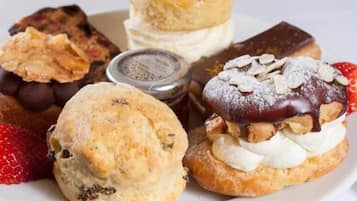 Diversos doces em um prato, incluindo um coberto com chocolate, um recheado com creme e um biscoito com morango.