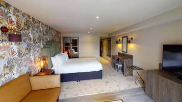 A hotel room with a bed, a desk, a TV, and a bathroom visible through an open door.