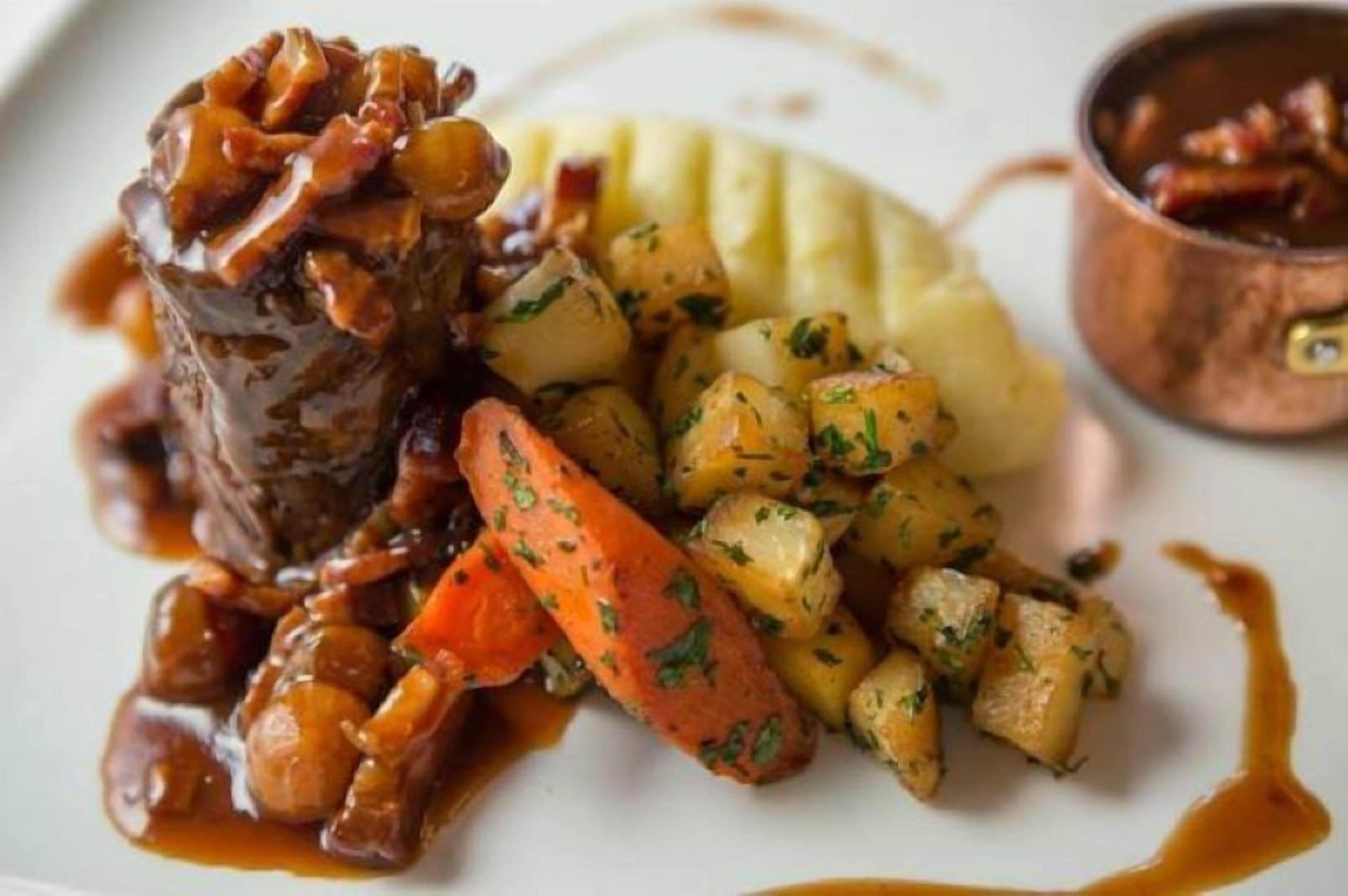 Un plato de comida con carne, papas y zanahorias.