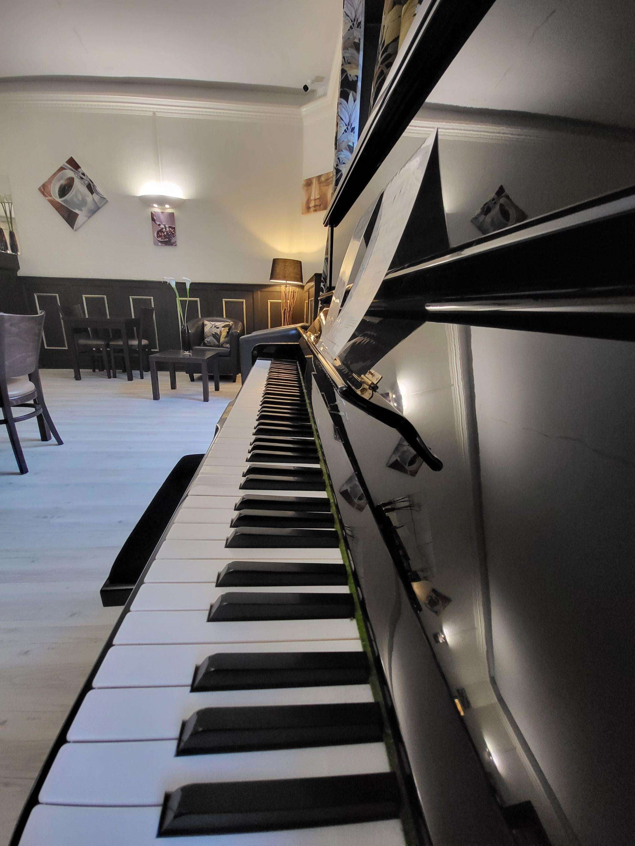 A piano in a room with chairs and a lamp.