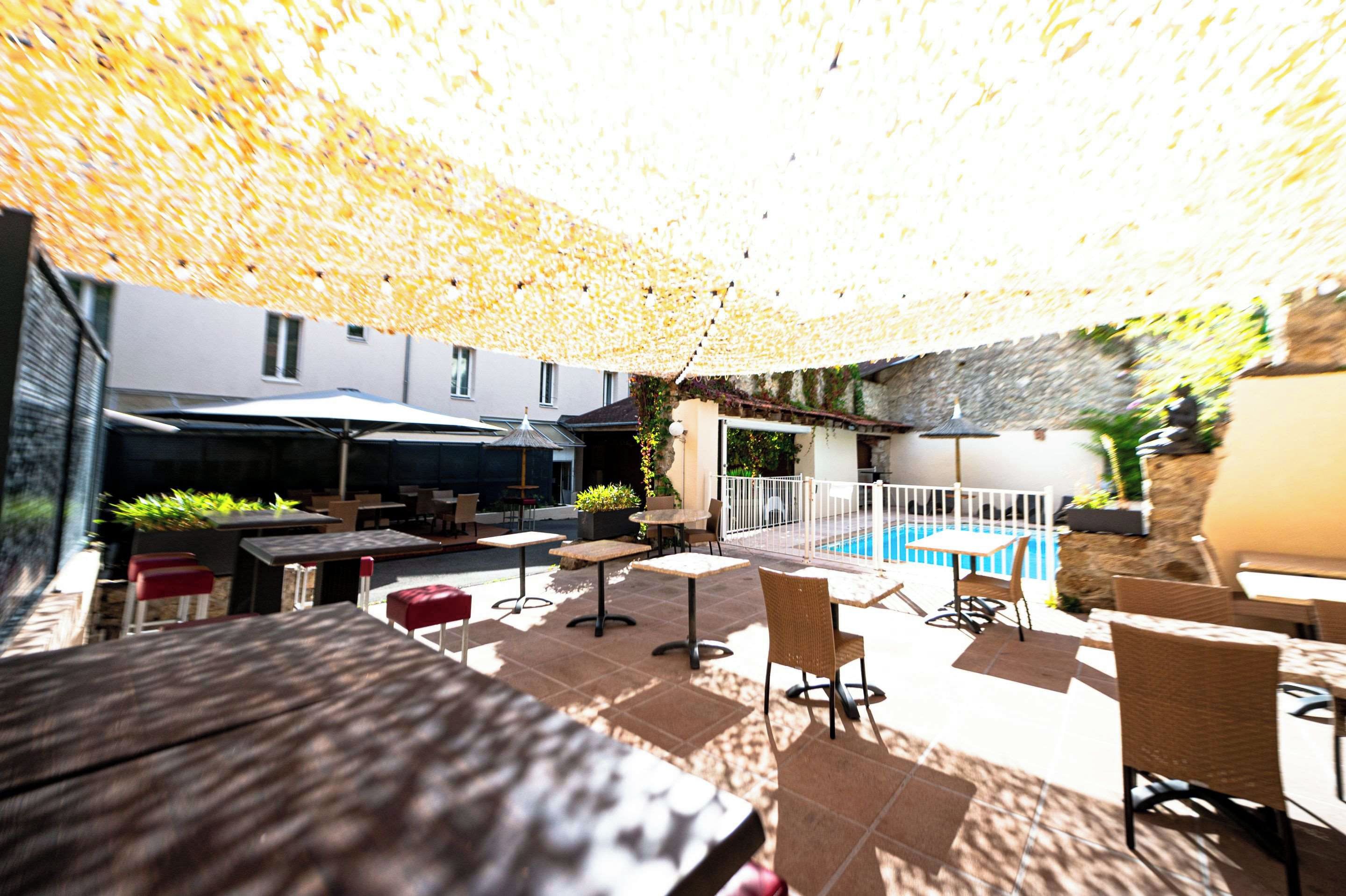 An outdoor seating area with tables and chairs, a pool, and a covered patio.