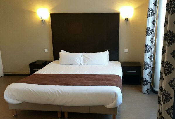 A hotel room with a large bed, two bedside tables, and a headboard with wall-mounted lights. - Brit Hotel Confort Auclair Gueret (Gueret)