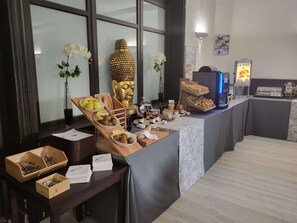 Un bufé de desayuno con diversos alimentos y una estatua de Buda.