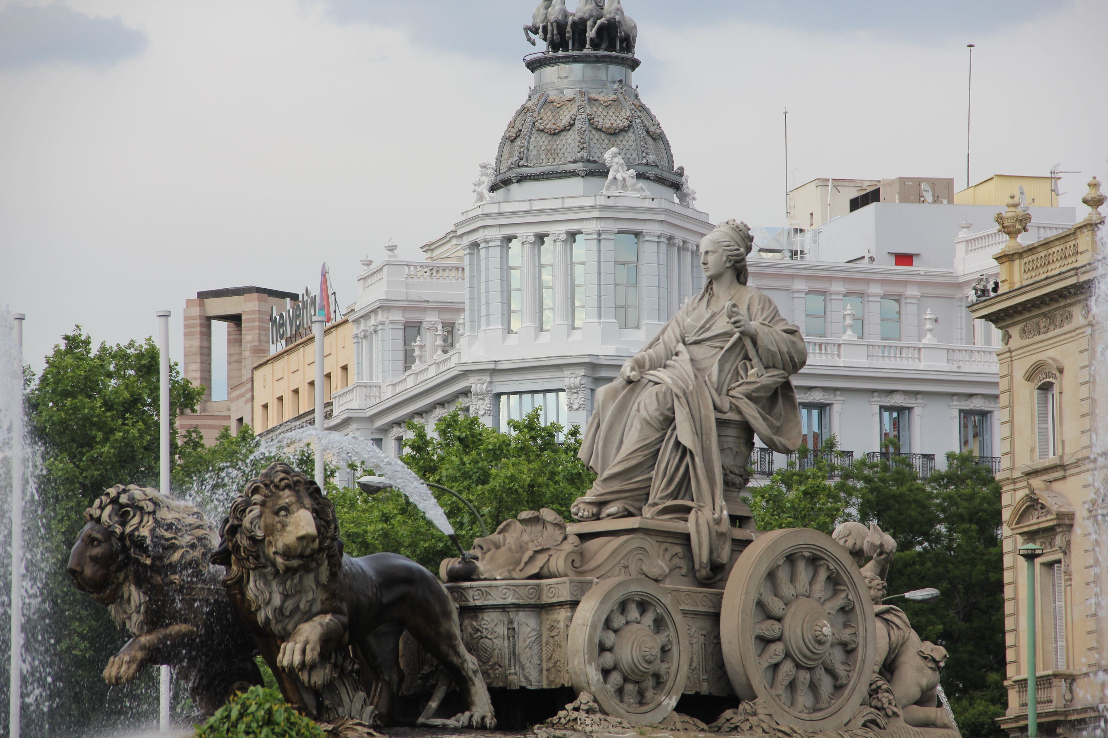 A statue of a seated figure on a carriage with a lion and an angel nearby.