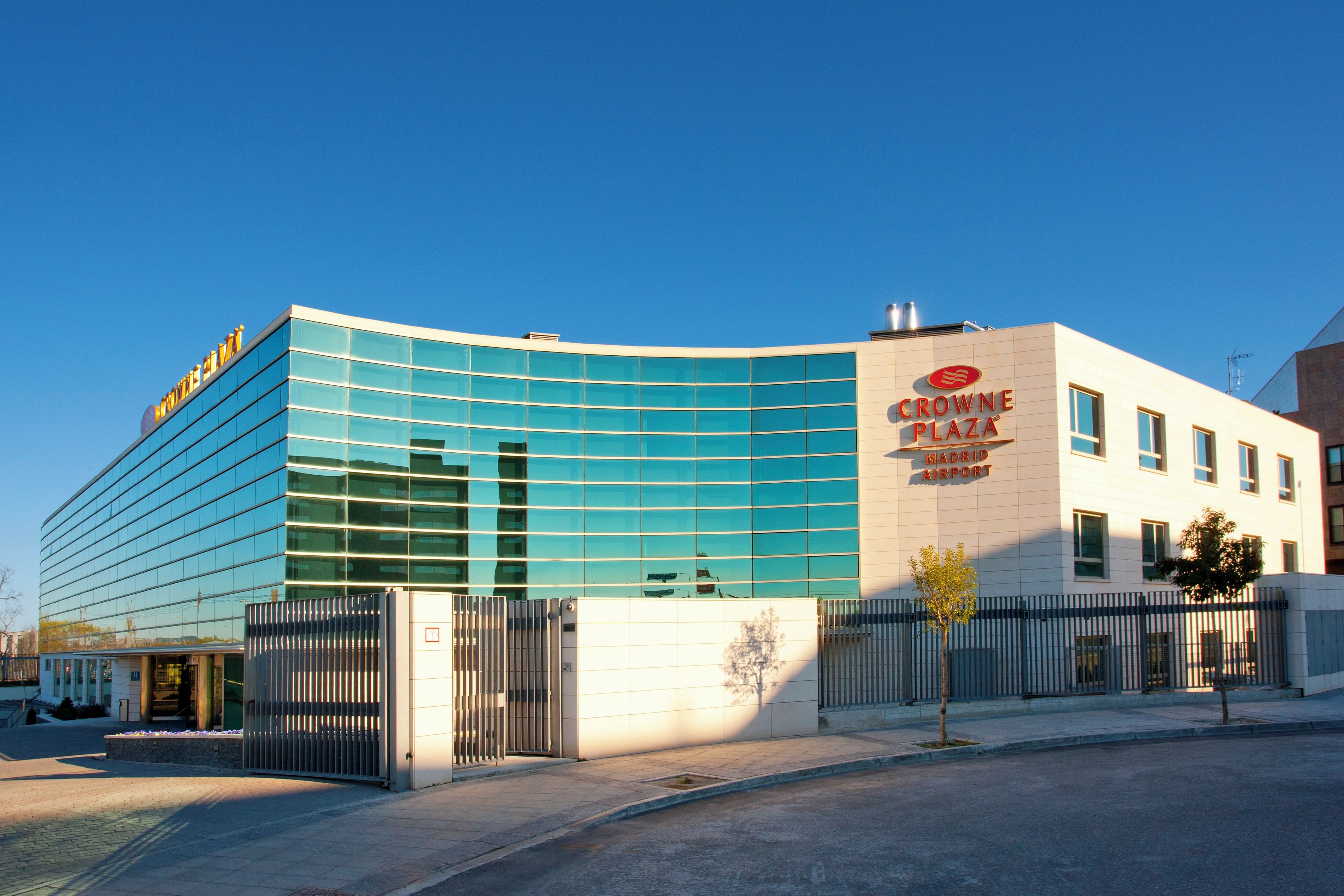 Un edificio moderno con fachada de vidrio y señalización para "Crown Plaza Madrid Airport".
