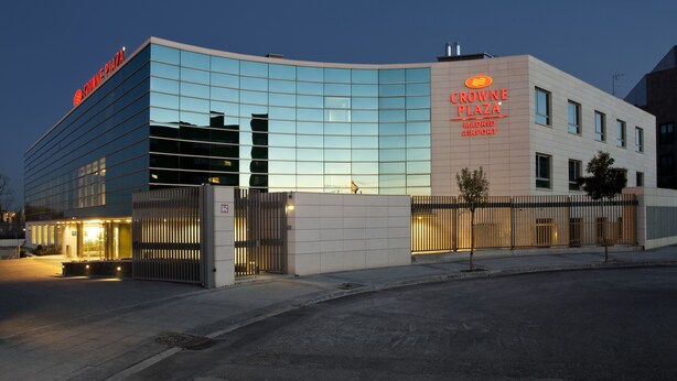 Un edificio moderno con fachada de vidrio y señalización de Crowne Plaza Madrid Airport.