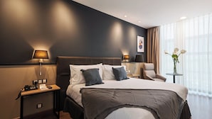 Una habitación de hotel moderna con una cama grande, lámparas de noche, un escritorio con teléfono y una silla.