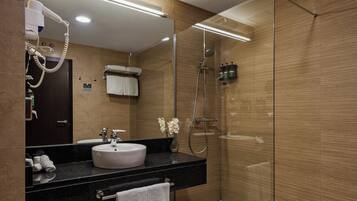Un baño moderno con un lavabo redondo, un espejo, un secador de pelo y una ducha.