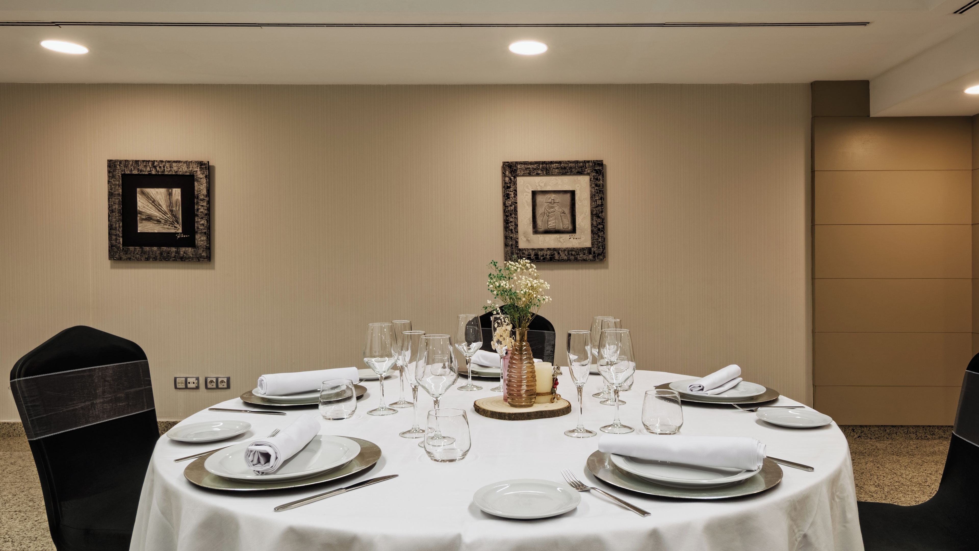 Een ronde eettafel met een witte tafelkleed, gedekt met borden, glazen en een middelpunt.