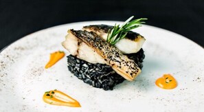Prato com peixe, um vegetal escuro e um acompanhamento.